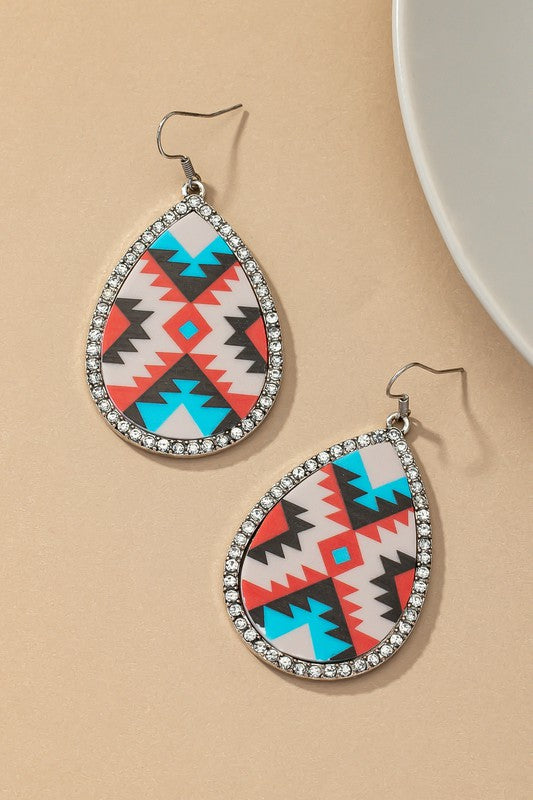 Introducing the Teardrop Aztec drop earrings with rhinestones, featuring a vibrant geometric pattern inspired by Aztec designs and highlighted with shimmering glass rhinestones set against a beige backdrop.