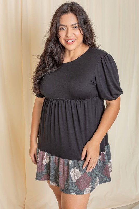 A person wearing the Floral Two Tone Tiered Mini Dress, featuring puff sleeves and a vibrant tie-dye hem, stands against a beige background, smiling.