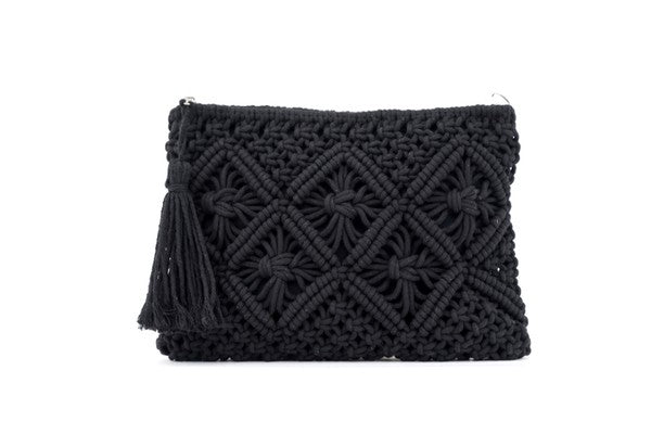 A person sits with the Macrame Tassel Clutch, which showcases a geometric pattern and tassel, secured with a zipper closure. They wear a white top and denim shorts that perfectly complement this stylish accessory.