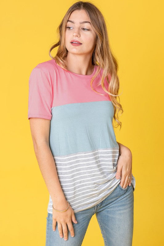 A person in a Sage Coral Black Grey Stripe Lavender Top made of polyester and jeans stands in a room with plants and white curtains.