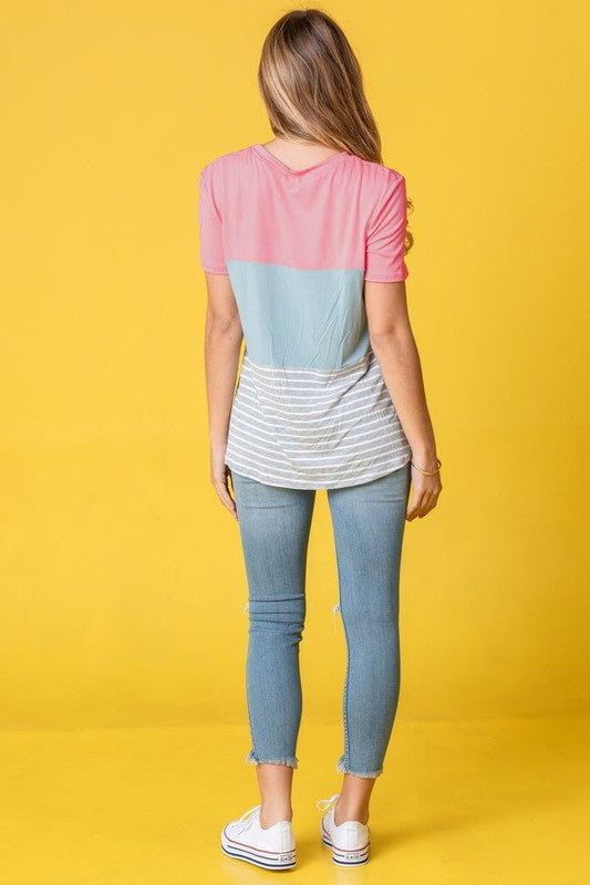 A person in a Sage Coral Black Grey Stripe Lavender Top made of polyester and jeans stands in a room with plants and white curtains.