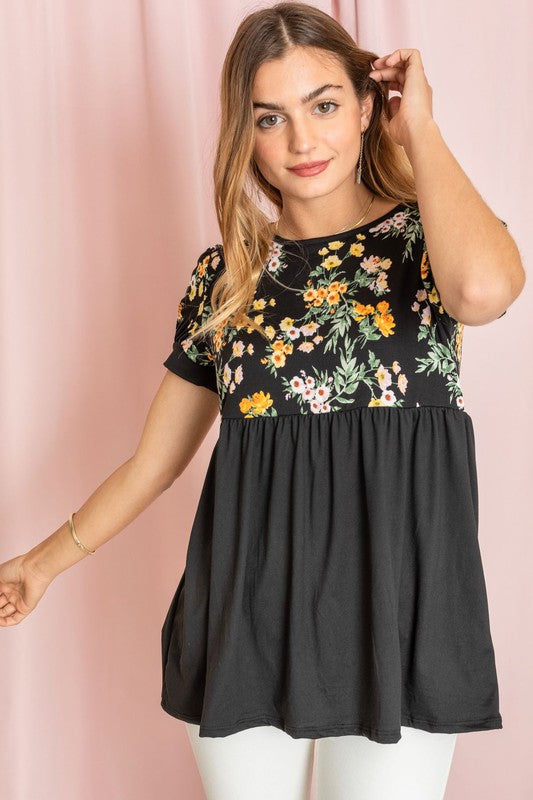 A person wearing a Baby Doll Floral Puff Sleeve Tunic and white pants stands gracefully against a pink background.