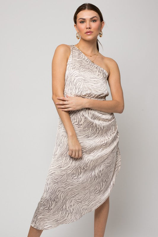 A woman gracefully poses in a sleeveless one-shoulder abstract print dress against a simple background.