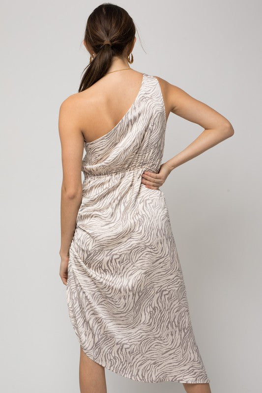 A woman gracefully poses in a sleeveless one-shoulder abstract print dress against a simple background.