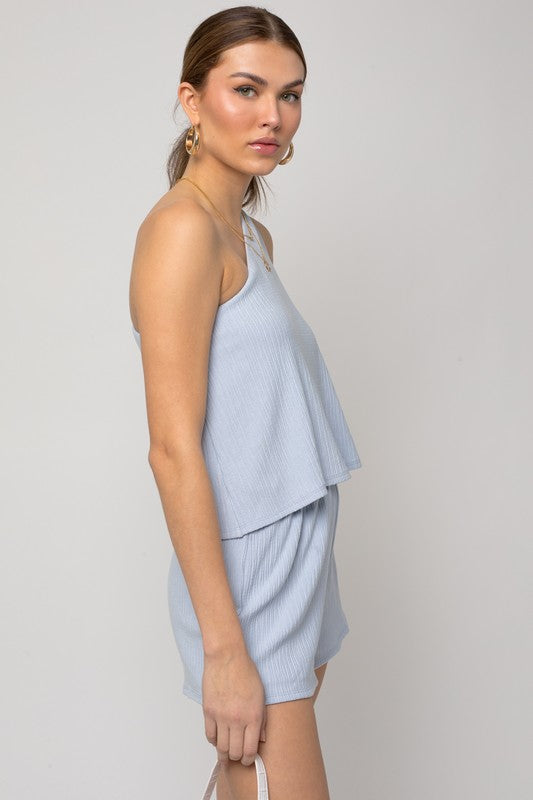 Person wearing the Sleeveless One Shoulder Layered Top Romper in a chic light blue shade, perfect for a stylish summer outfit, standing against a neutral background.