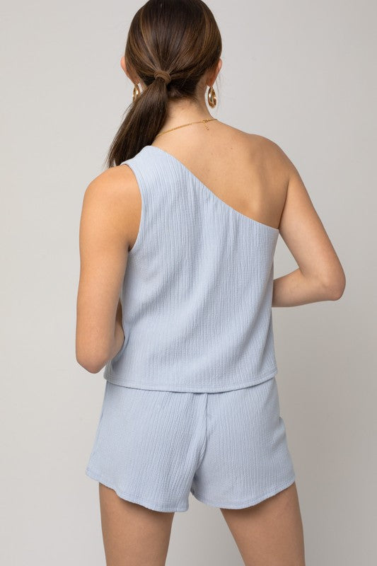 Person wearing the Sleeveless One Shoulder Layered Top Romper in a chic light blue shade, perfect for a stylish summer outfit, standing against a neutral background.