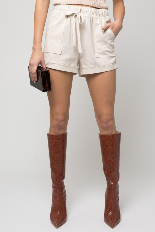 Individual wearing Elastic Waist Front Pocket Roll-Up Shorts in light green.