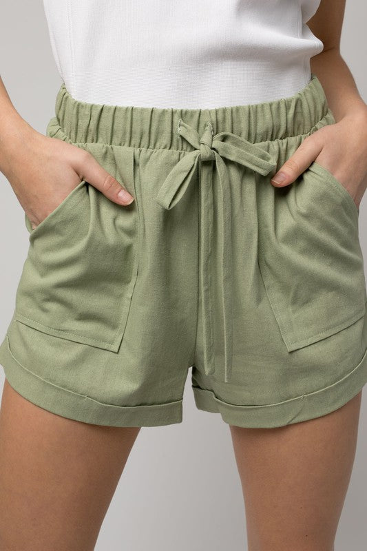 Individual wearing Elastic Waist Front Pocket Roll-Up Shorts in light green.