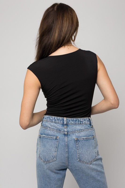 A person wearing a Cap Sleeve Square Neck Bodysuit and jeans holds a black handbag, showcasing a true fashion essential.