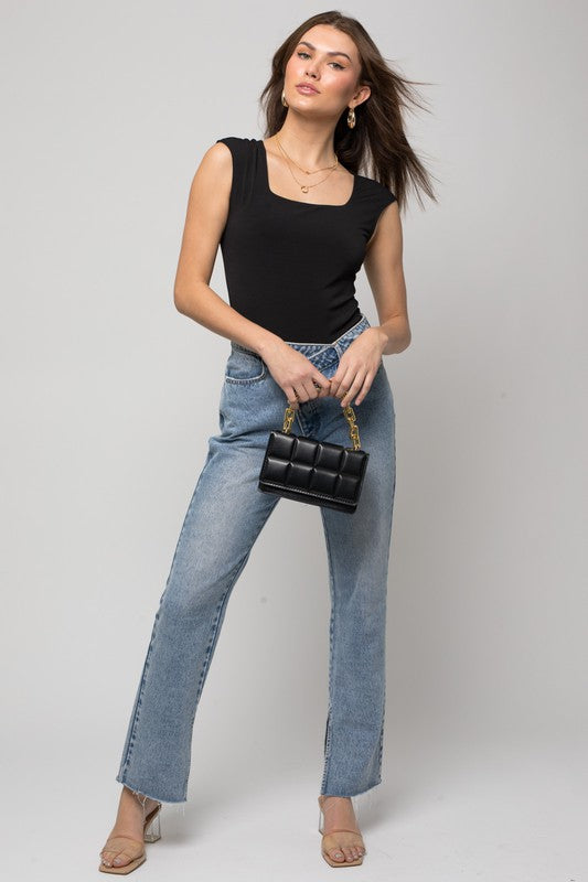 A person wearing a Cap Sleeve Square Neck Bodysuit and jeans holds a black handbag, showcasing a true fashion essential.