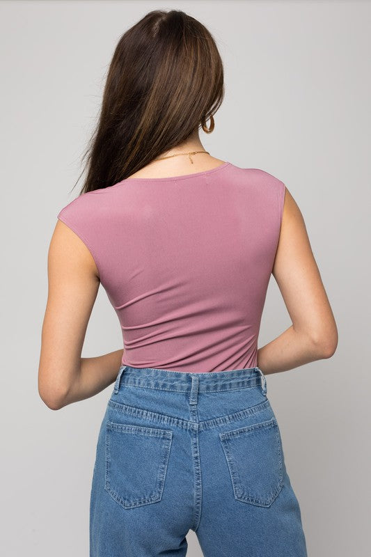 A person wearing a Cap Sleeve Square Neck Bodysuit and jeans holds a black handbag, showcasing a true fashion essential.