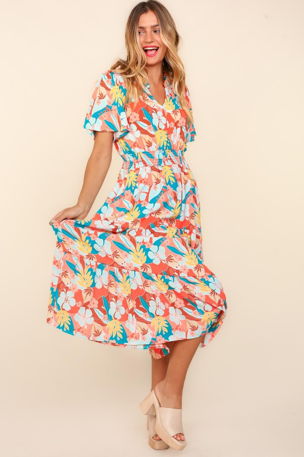 A person wearing the Haptics Full Size Tropical Floral Tiered Dress with Side Pockets and beige platform sandals stands against a plain background.