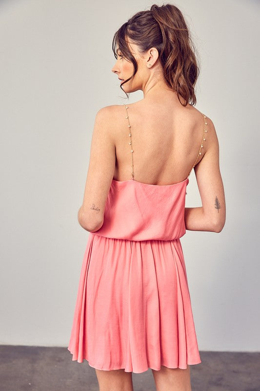 A woman wearing the Cowl Neck Beaded Strap Dress poses indoors against a simple backdrop, glancing to the side. Ideal for special occasions, this elegant piece is enhanced by its sleeveless design.