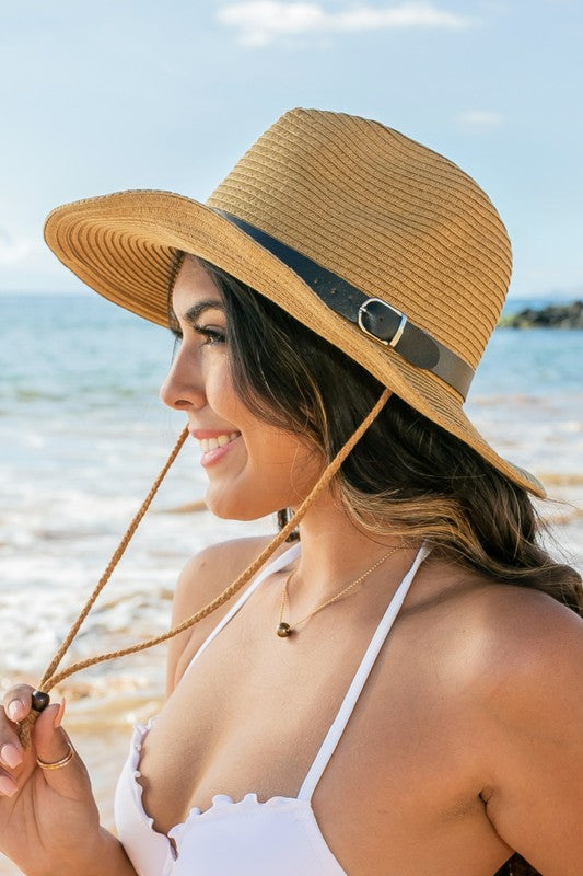 Woman holding a Drawstring Panama Hat on the beach.