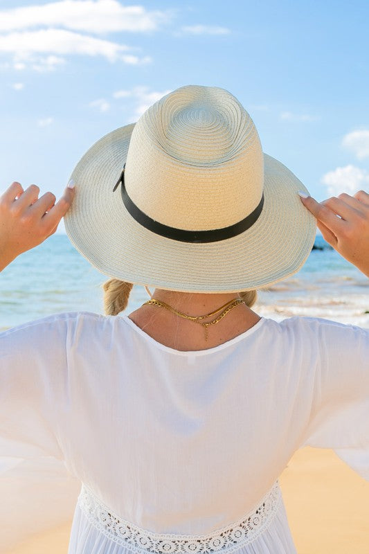 Woman holding a Drawstring Panama Hat on the beach.
