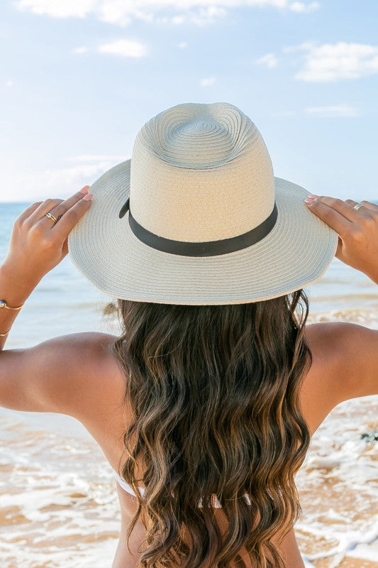 Woman holding a Drawstring Panama Hat on the beach.