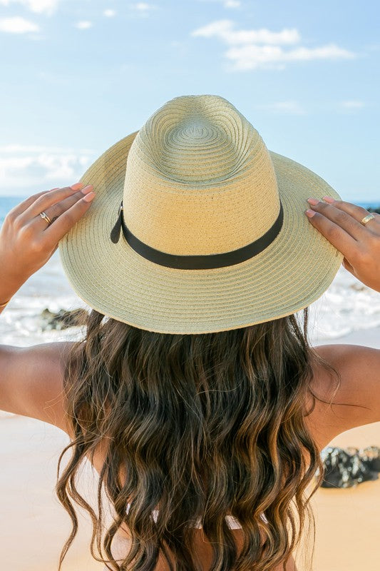 Woman holding a Drawstring Panama Hat on the beach.