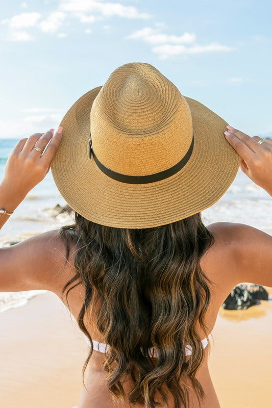 Woman holding a Drawstring Panama Hat on the beach.