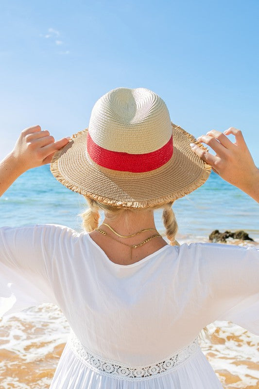 Woman smiling on the beach while holding onto her Fray-Edge Color Block Straw Panama Fedora Hat.