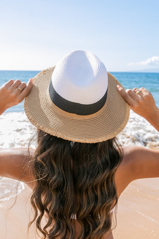 Woman smiling on the beach while holding onto her Fray-Edge Color Block Straw Panama Fedora Hat.