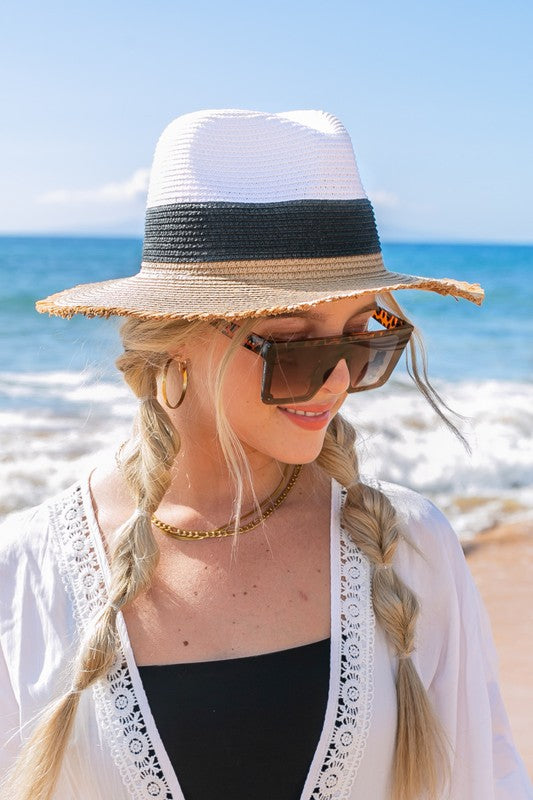 Woman smiling on the beach while holding onto her Fray-Edge Color Block Straw Panama Fedora Hat.