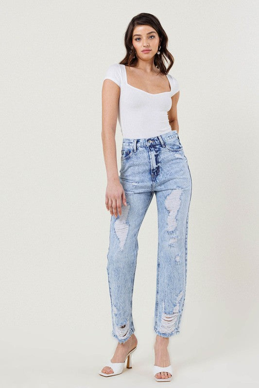 A woman wearing a white top and the High Waisted Straight Leg in Vintage Acid Wash jeans stands against a plain background, paired with white heeled sandals.