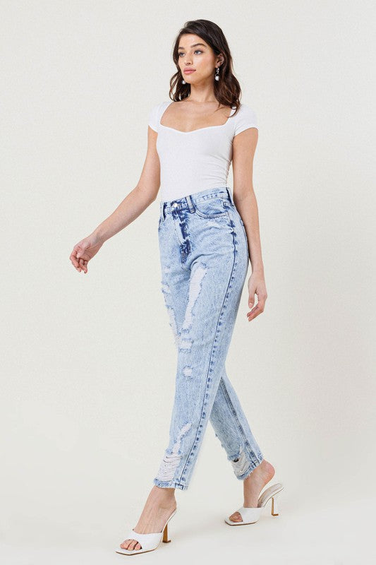 A woman wearing a white top and the High Waisted Straight Leg in Vintage Acid Wash jeans stands against a plain background, paired with white heeled sandals.