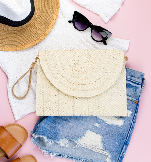 A woman carrying a Straw Foldover Convertible Clutch, easily converts it into a sleek clutch with its optional crossbody strap.