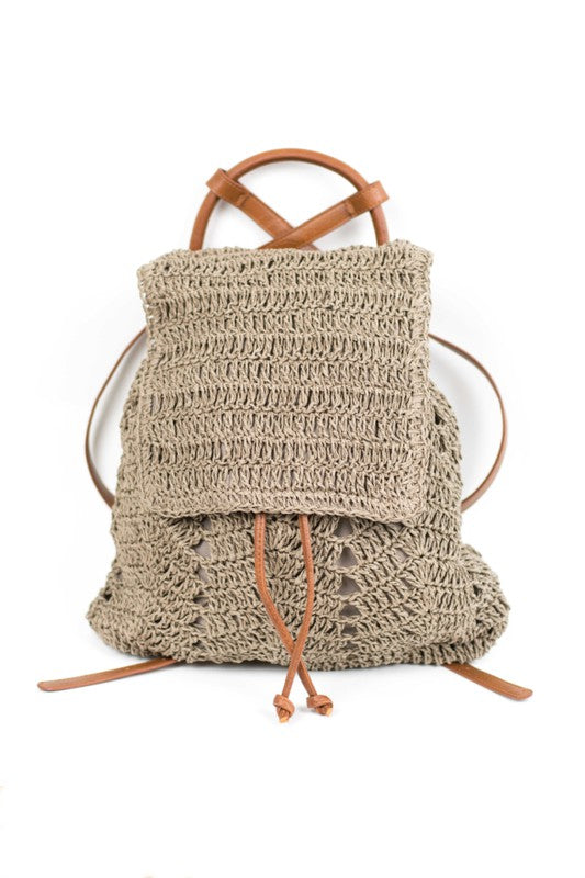 A person wearing a straw hat and white tank top carries the elegant Woven Straw Backpack, featuring charming PU leather straps.