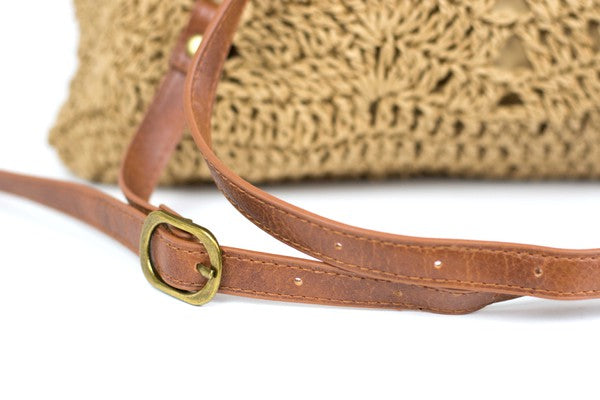 A person wearing a straw hat and white tank top carries the elegant Woven Straw Backpack, featuring charming PU leather straps.