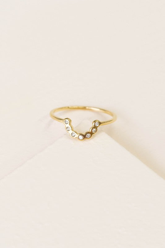 The All Smiles Ring showcases a sleek, minimalistic design characterized by its elegant curved v-shape and finished with a luxurious 14k gold plating. It is embellished with delicate round gemstones and beautifully presented against a white background.