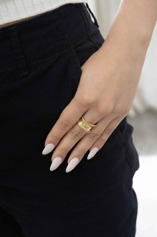 The Sculpted Adjustable Ring, plated in 14k gold with a smooth, shiny finish, is elegantly displayed on a light, textured background.