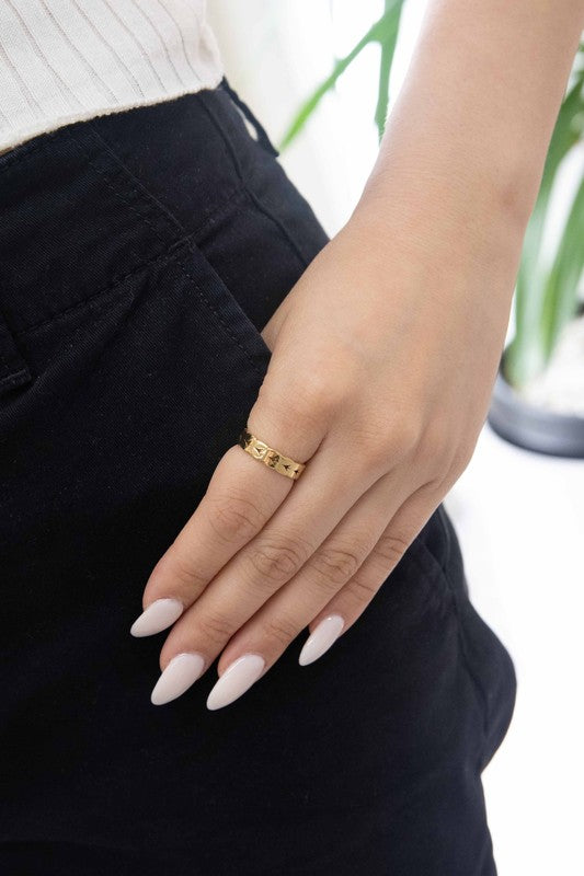 The Braided Ring, a 14k gold-plated piece adorned with engraved star patterns, rests on a white surface, exuding elegance and charm.