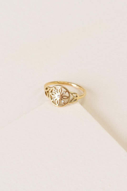 The Dreamer Ring boasts a sunburst design adorned with a small central gem, beautifully set against a textured off-white background. With its 14k gold-plated finish, this ring captivates with timeless elegance.