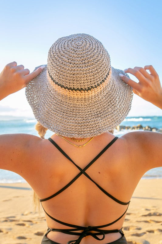 Woman smiling with sunglasses and a Stripe Accent Straw Bucket Hat at the beach.