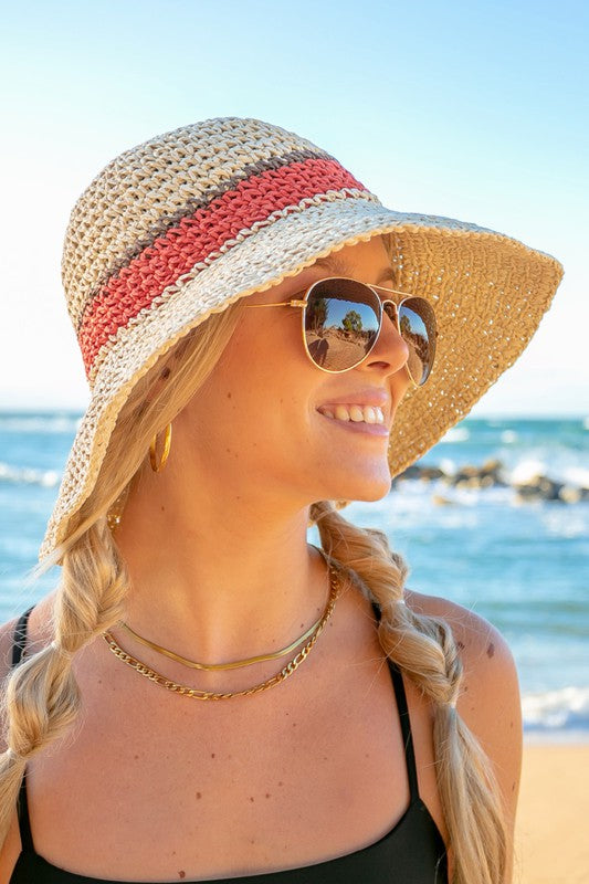 Woman smiling with sunglasses and a Stripe Accent Straw Bucket Hat at the beach.