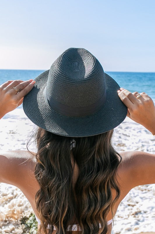 Young woman in a Classic Straw Panama Fedora Hat with a black cotton band smiling on the beach.