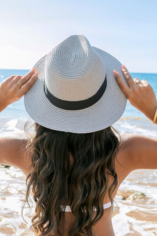 Young woman in a Classic Straw Panama Fedora Hat with a black cotton band smiling on the beach.