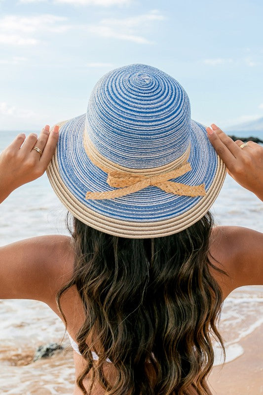 A person holding onto a Multi-Stripe Bow Accent Bucket Sunhat while facing the sea.