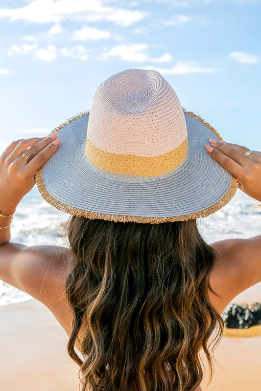 Woman holding a Fray-Edge Rattan Band Straw Panama Fedora Hat at the beach.