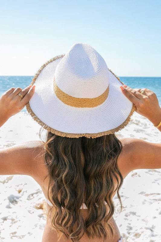 Woman holding a Fray-Edge Rattan Band Straw Panama Fedora Hat at the beach.