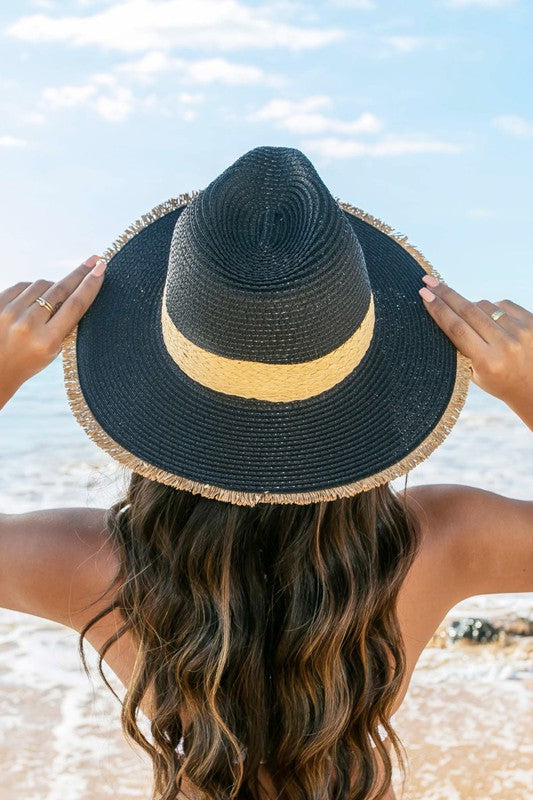 Woman holding a Fray-Edge Rattan Band Straw Panama Fedora Hat at the beach.