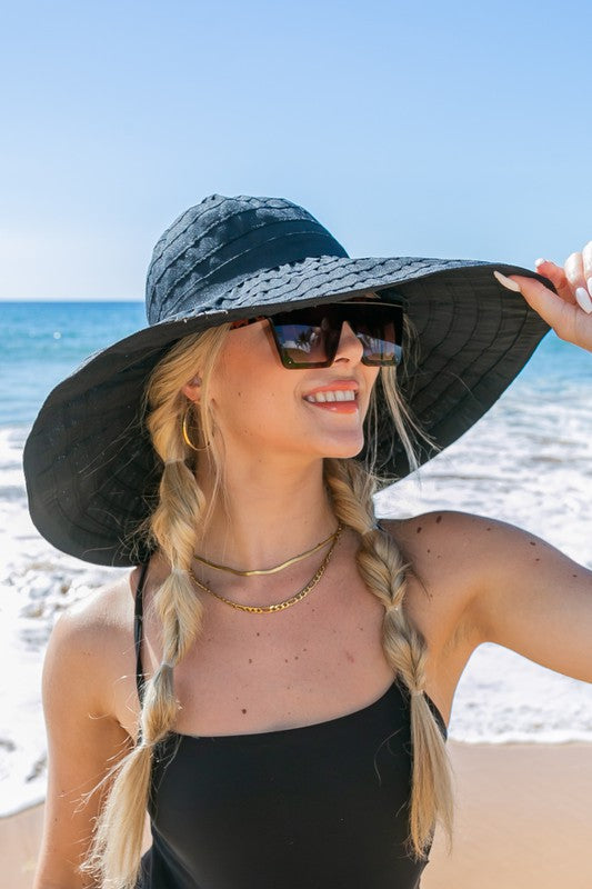 Woman holding a Classic Bow Accent Sunhat Extra Wide Brim at the beach.
