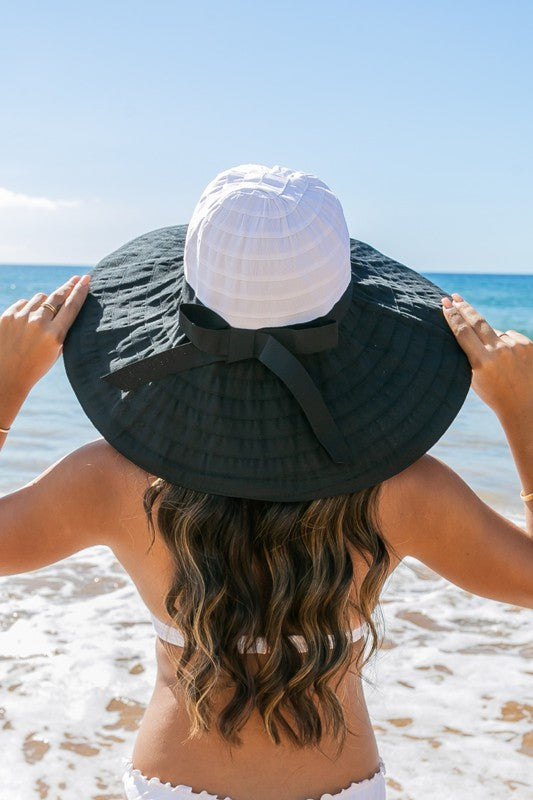 Woman holding a Classic Bow Accent Sunhat Extra Wide Brim at the beach.