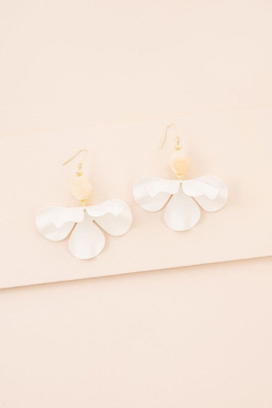 Snowdrop Hook Earrings: These elegant earrings showcase white, petal-shaped drops complemented by hooks with 10k gold plating, all beautifully presented on a beige background.