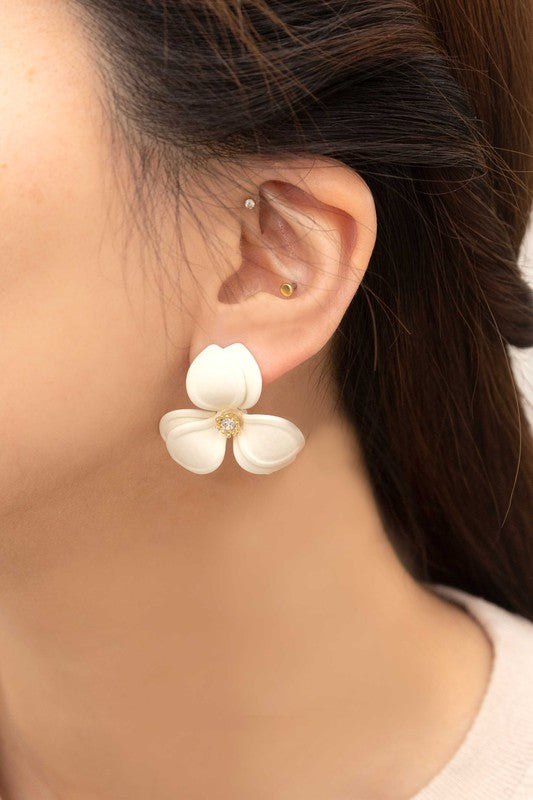 Close-up of a pair of cream-colored Gardenia Statement Earrings set against a soft beige backdrop, showcasing the intricate detail of their sterling silver craftsmanship.