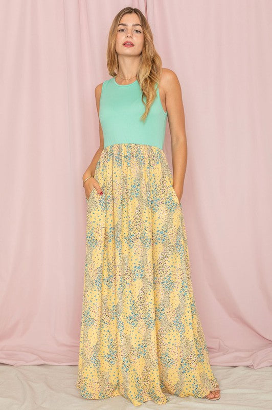 A woman in a Meadow Floral Print Maxi Dress stands against a pink curtain backdrop.