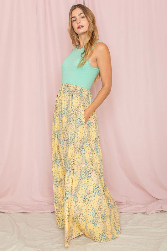 A woman in a Meadow Floral Print Maxi Dress stands against a pink curtain backdrop.