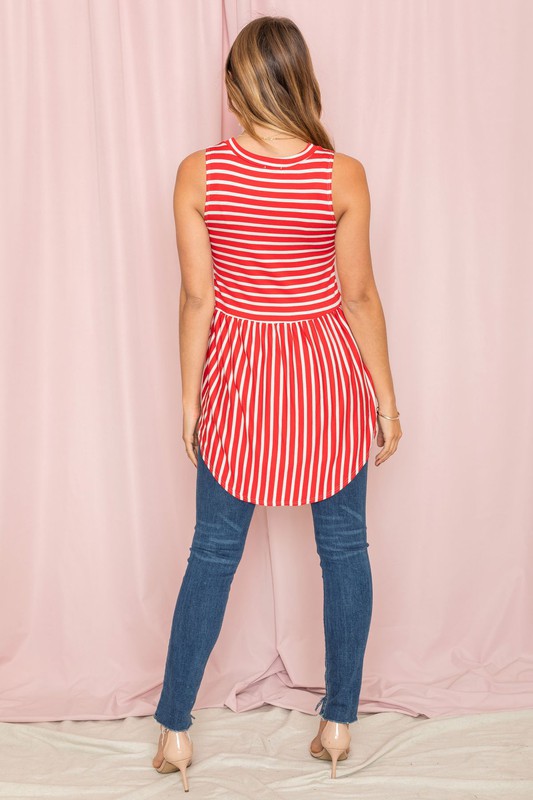 Against a pink background, a woman in a sleeveless blue and white striped top captures the casual elegance of the Stripe High Waist Tunic, proudly made in the United States.