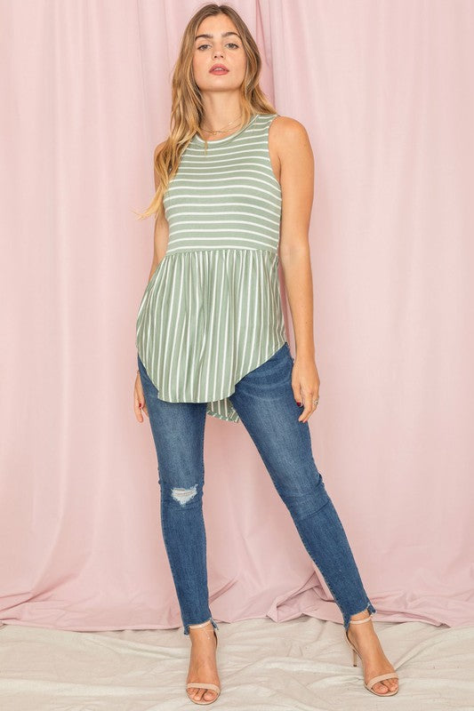 Against a pink background, a woman in a sleeveless blue and white striped top captures the casual elegance of the Stripe High Waist Tunic, proudly made in the United States.